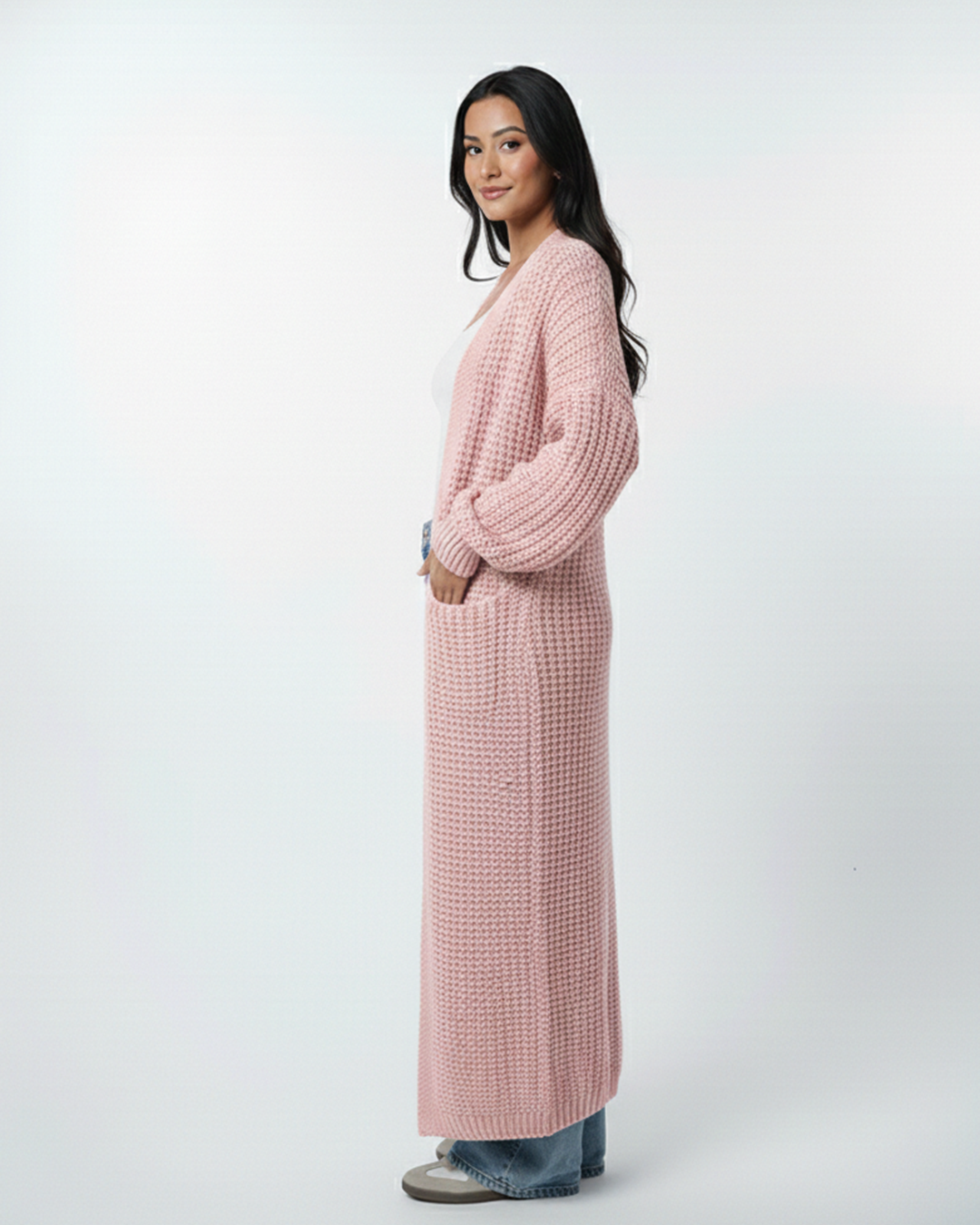 Woman wearing a long pink cardigan on a white background